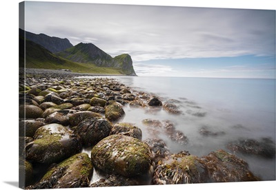 Rocks on the beach frame the calm clear sea, Unstad, Vestvagoy, Lofoten Islands, Norway