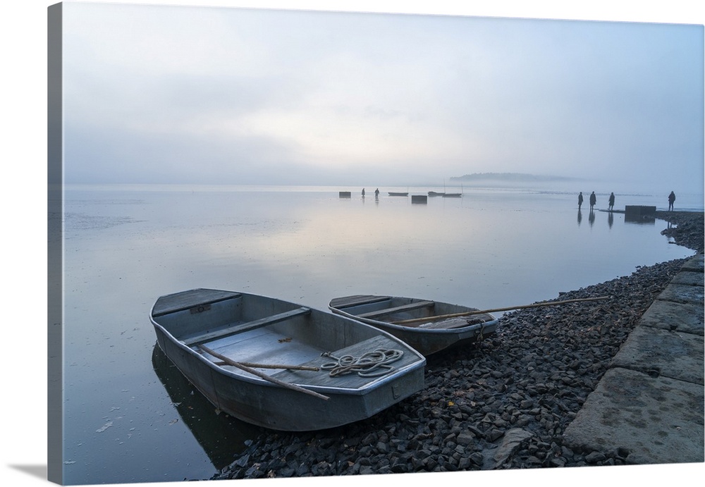 Rowing boats on shore  with fishermen in background preparing for fish harvest on foggy morning, Rozmberk Pond, UNESCO Bio...