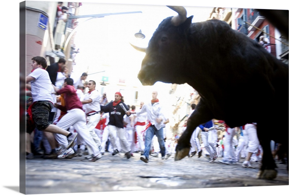 A bull in motion chasing a blurry crowd. The motion blur effect suggests a sense of speed or conveys the passage of time.