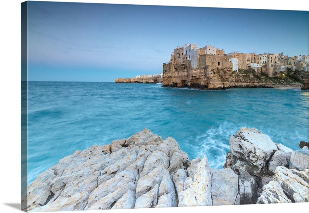 Turquoise sea at dusk framed by the old town perched on the rocks, Polignano a Mare, Province of Bari, Apulia, Italy