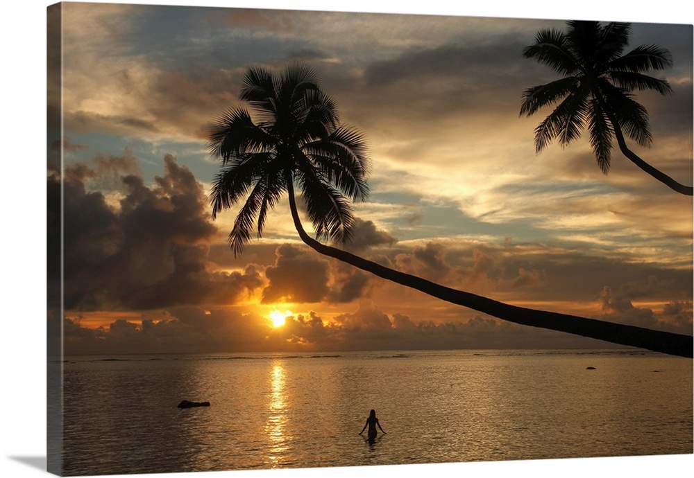 Silhouette of leaning palm trees and a woman at sunrise on Taveuni Island, Fiji