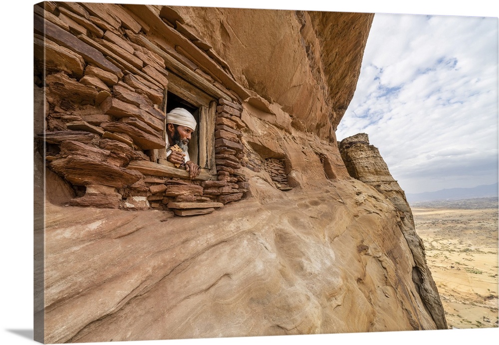 Priest looking out from a small window carved into rocks in Abuna Yemata Guh church, Gheralta Mountains, Tigray Region, Et...