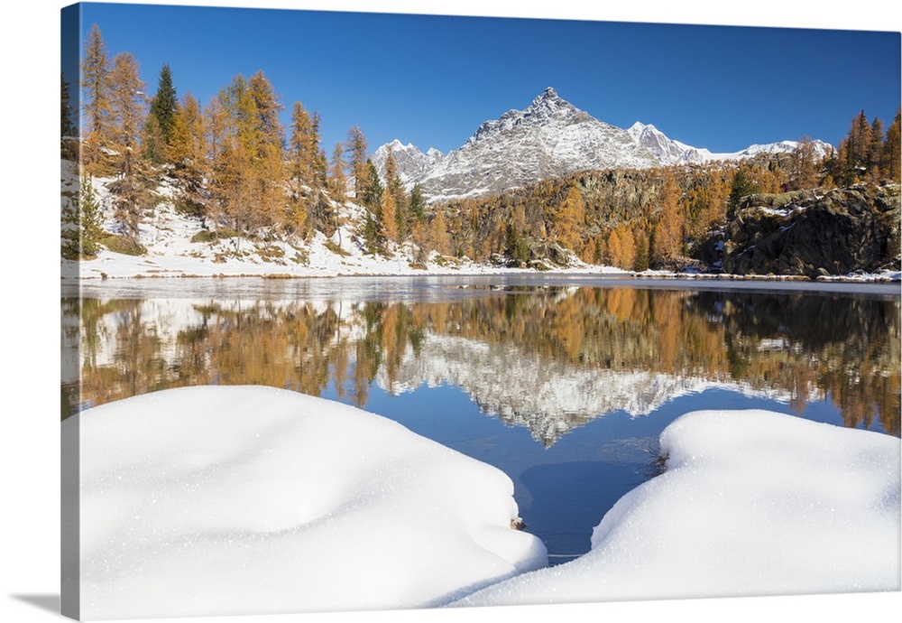 The snowy peaks are reflected in the frozen Lake Mufule, Malenco Valley, Province of Sondrio, Valtellina, Lombardy, Italy