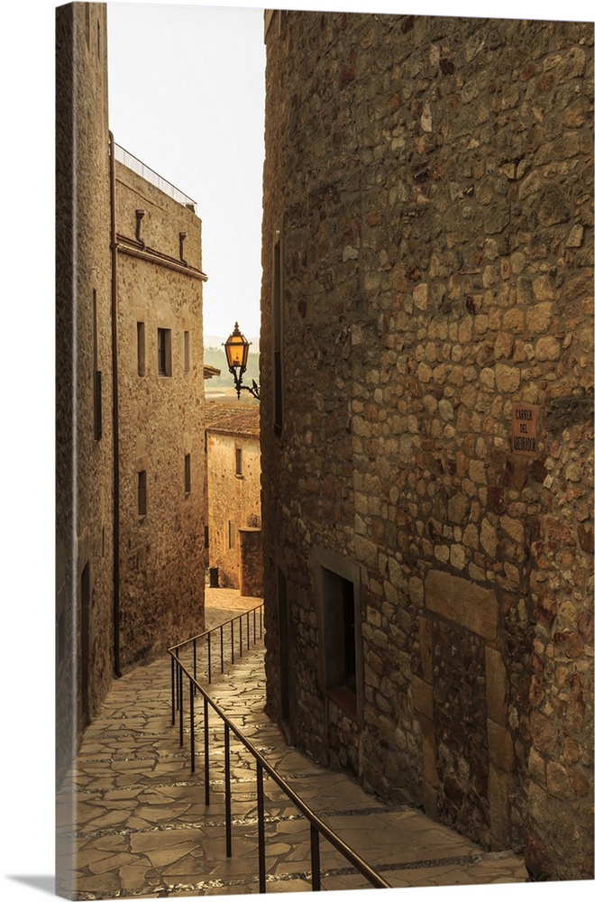 Steep and narrow winding street in gorgeous medieval hilltop walled village, Pals, Baix Emporda, Girona, Catalonia, Spain,...