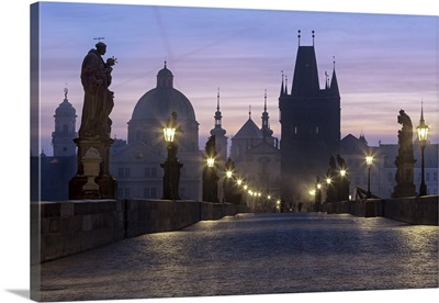 Street lanterns and old statues frame the historical buildings on Charles Bridge, Prague