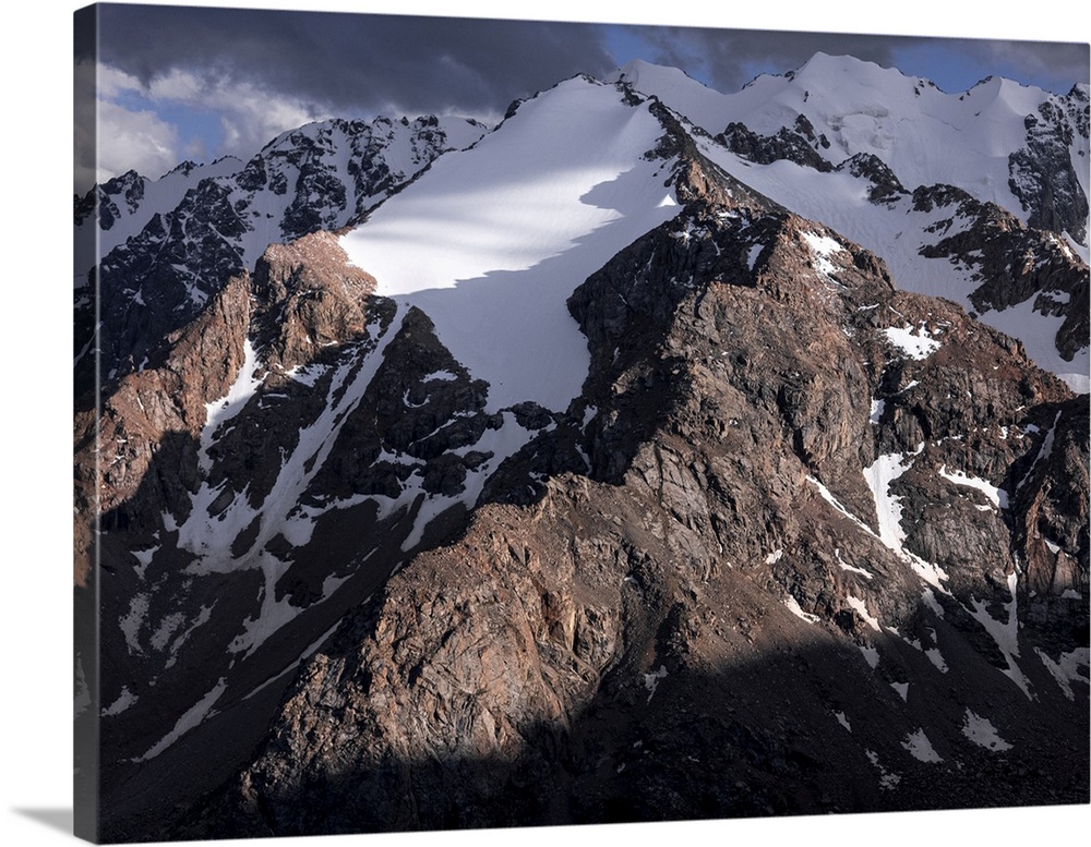 Stunning mountainous landscape of Kyrgyzstan illuminated by fading sunlight and shadowy clouds, Kyrgyzstan, Central Asia, ...