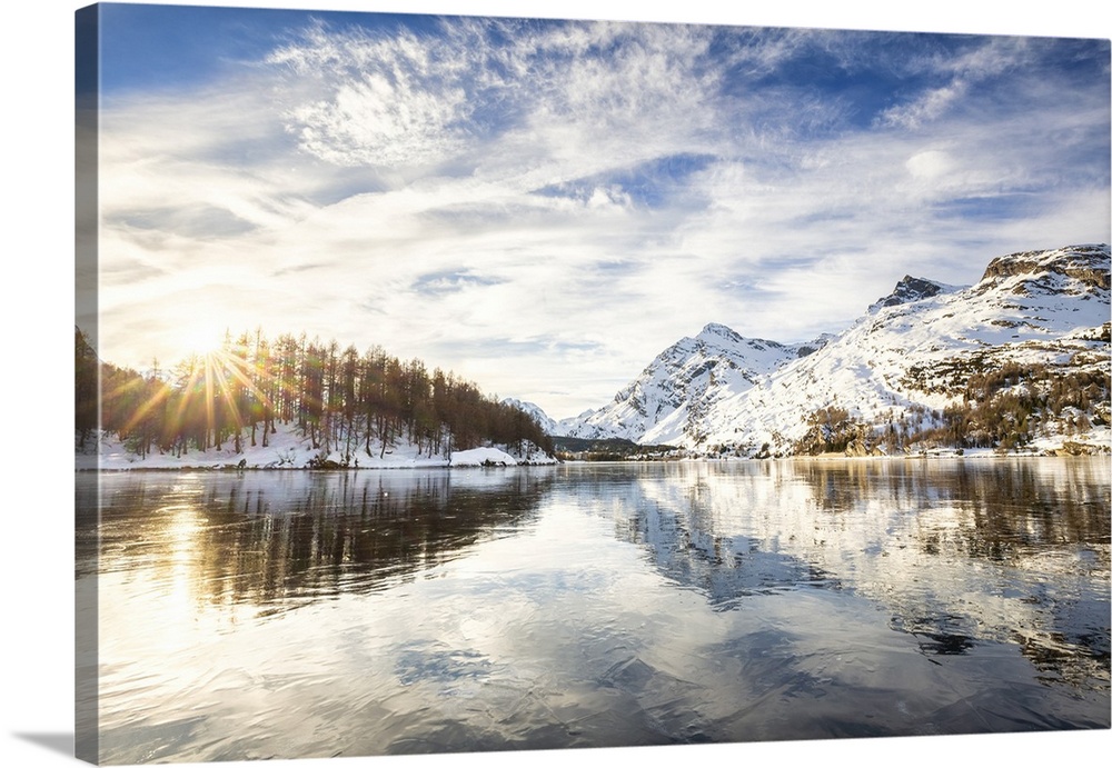 The sun illuminates the icy surfaces of Lake Sils, Engadine Valley, Graubunden, Swiss Alps, Switzerland, Europe