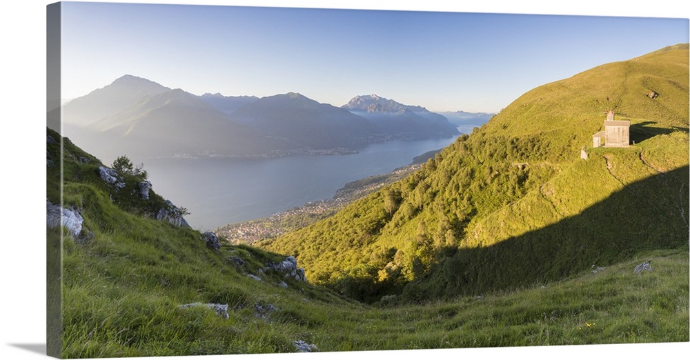 Sun on Church of San Bernardo lights up the landscape around the blue water of Lake Como at dawn, Musso, Lombardy, Italy, ...