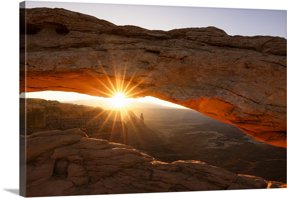 Sunlight envelops the Canyonlands Valley during a summer sunrise, framed by Mesa Arch, Utah, United States of America, Nor...