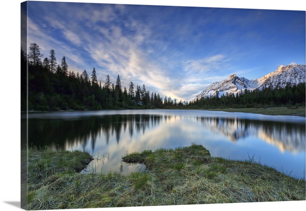 Sunrise frames the snowy peaks reflected in Lake Entova, Malenco Valley, Province of Sondrio, Valtellina, Lombardy, Italy