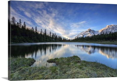 Sunrise frames the snowy peaks reflected in Lake Entova, Malenco Valley, Lombardy, Italy