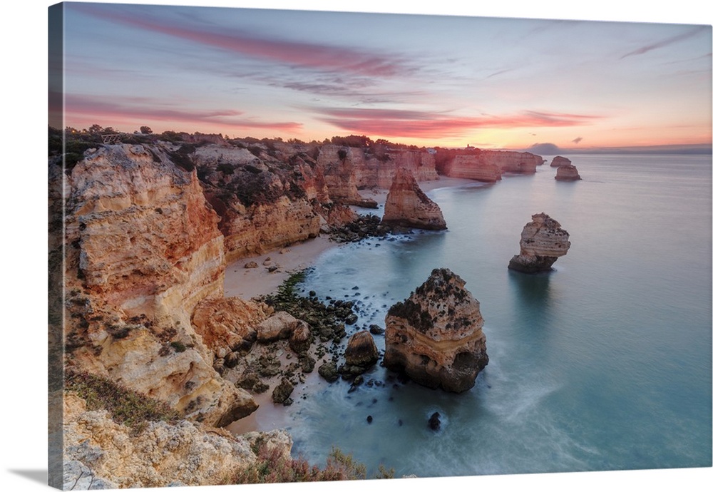 Sunrise on cliffs framed by turquoise water of the ocean, Praia da Marinha, Caramujeira, Lagoa Municipality, Algarve, Port...