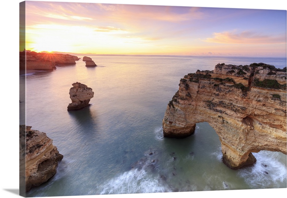 Sunrise on cliffs framed by turquoise water of the ocean, Praia da Marinha, Caramujeira, Lagoa Municipality, Algarve, Port...