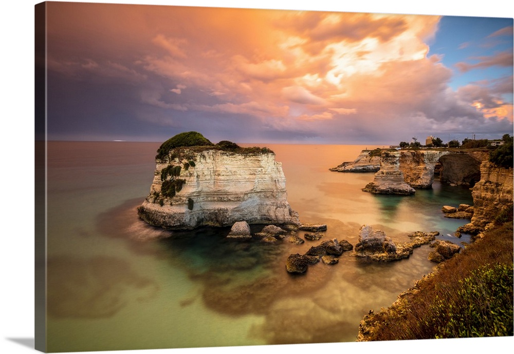 Sunset frames the high cliffs known as Faraglioni di Sant'Andrea and the turquoise sea, province of Lecce, Apulia, Italy