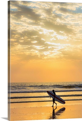 Surfer with long board at sunset on popular Playa Guiones surf beach, Costa Rica
