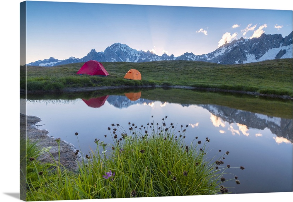 Camping tents in the green meadows surrounded by flowers and alpine lake, Mont De La Saxe, Courmayeur, Aosta Valley, Italy