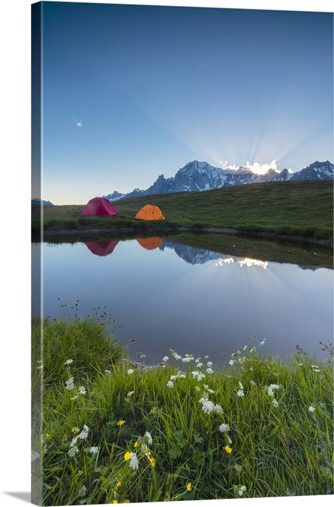 Camping tents in the green meadows surrounded by flowers and alpine lake, Mont De La Saxe, Courmayeur, Aosta Valley, Italy