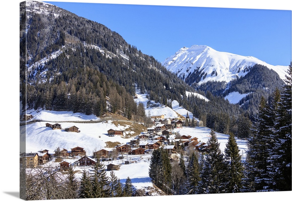 The alpine village of Langwies framed by woods and snowy peaks, district of Plessur, Canton of Graubunden, Swiss Alps, Swi...