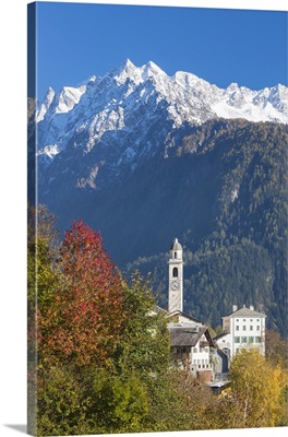 The colorful trees frame the alpine church and the snowy peaks, Switzerland