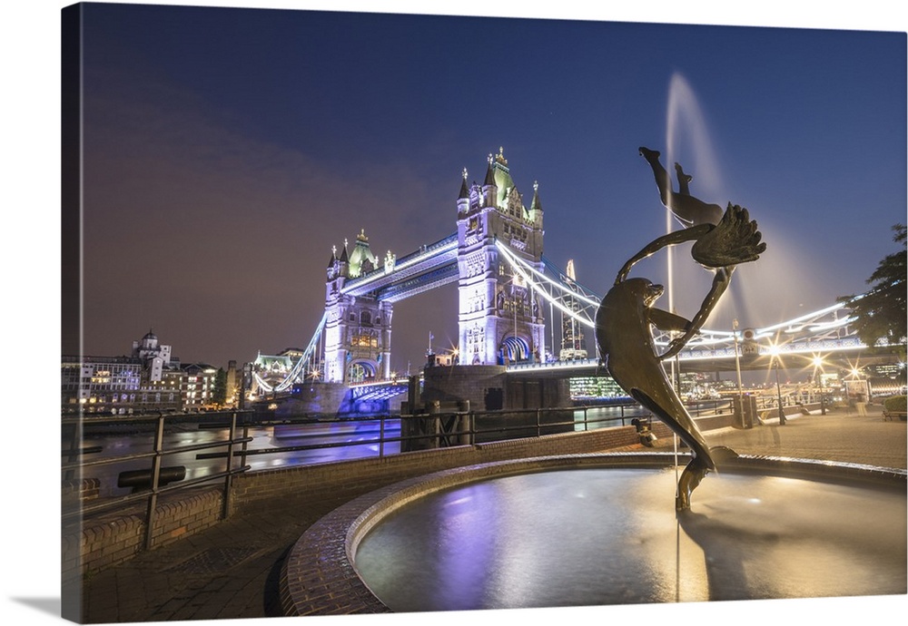 The Girl With A Dolphin Fountain frames Tower Bridge reflected in the River Thames at night, London, England, United Kingd...