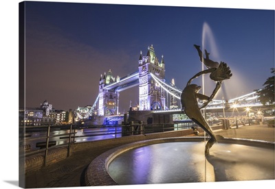 The Girl With A Dolphin Fountain frames Tower Bridge reflected in the River Thames