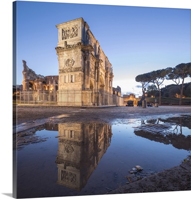 The historical Arch of Constantine reflected in a puddle at dusk, Rome, Lazio, Italy