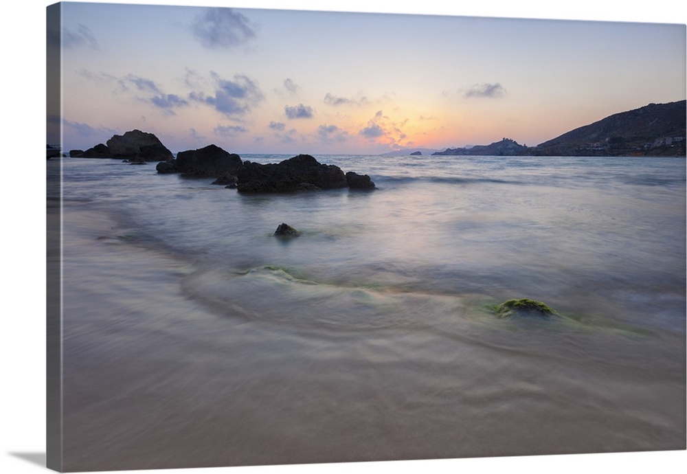 The last lights of the sunset are reflected on sea waves and sandy beach, Licata, Province of Agrigento, Sicily, Italy