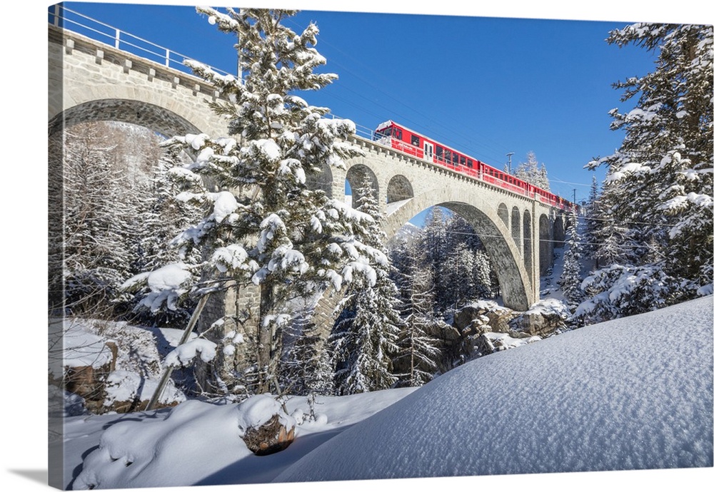 The red train on viaduct surrounded by snowy woods, Cinuos-Chel, Canton of Graubunden, Engadine, Switzerland