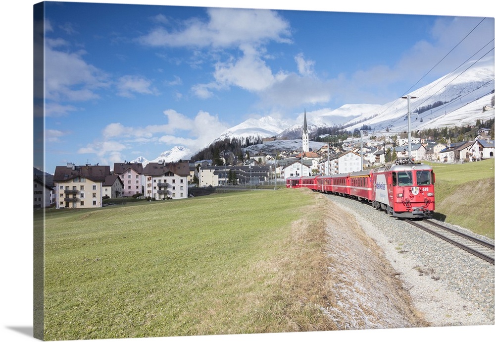 The red train runs across the alpine village of Zuoz in spring, Maloja, Canton of Graubunden, Engadine, Switzerland, Europe