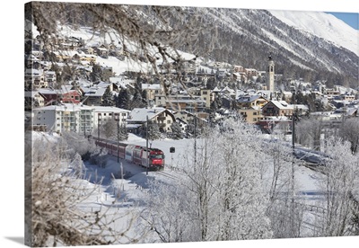The red train runs across the snowy landscape around Samedan, Switzerland