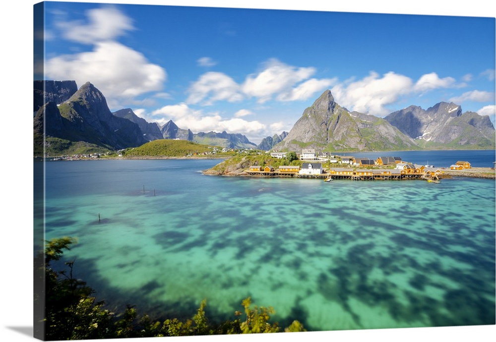 The turquoise sea frames the typical fishing village surrounded by rocky peaks, Sakrisoy, Reine, Moskenesoya, Lofoten Isla...