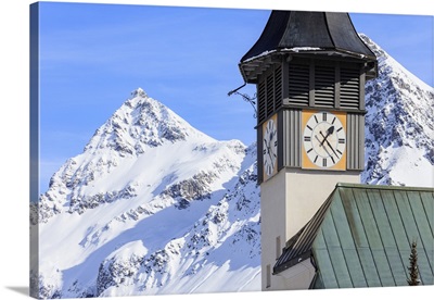 The typical alpine bell tower frames the snowy peaks, Swiss Alps, Switzerland