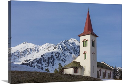 The white alpine church framed by snowy peaks, Bregaglia Valley,  Engadine, Switzerland