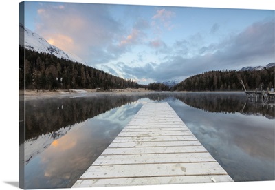 The wooden deck frames Lej Da Staz at dawn, St. Moritz, Switzerland