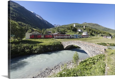 Typical red Swiss train on Hospental Viadukt surrounded by creek and green meadows