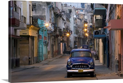 View along quiet street at dawn showing old American car, Havana, Cuba