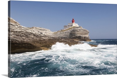 Waves of the sea crashing on the granite white cliffs and lighthouse, Corsica, France