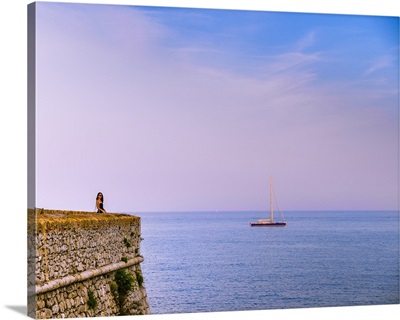 Woman alone at sunset next to the sea, Antibes, Cote d'Azur, French Riviera, France