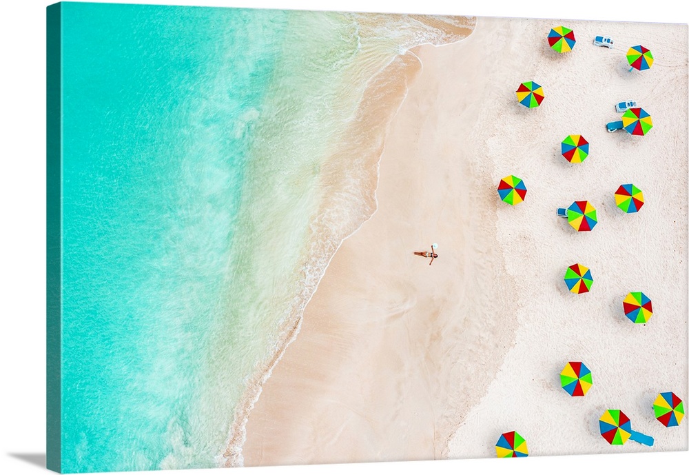 Aerial view of woman in bikini sunbathing on a tropical beach next to colorful umbrellas, Antigua, West Indies, Caribbean,...