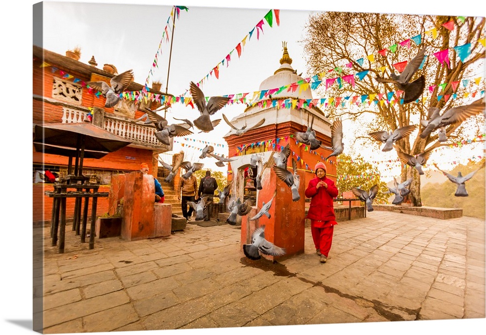 Woman walking and praying with pigeons at the hilltop temple, Bhaktapur, Kathmandu Valley, Nepal