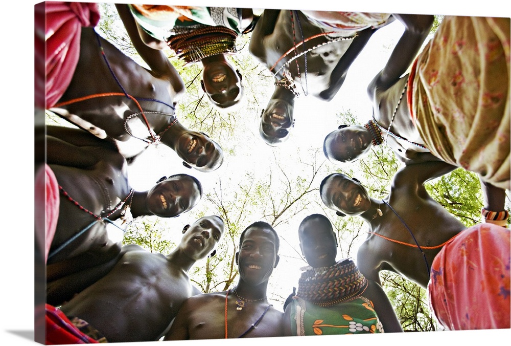 Photograph of natives in a circle looking down at camera with forest as back drop.