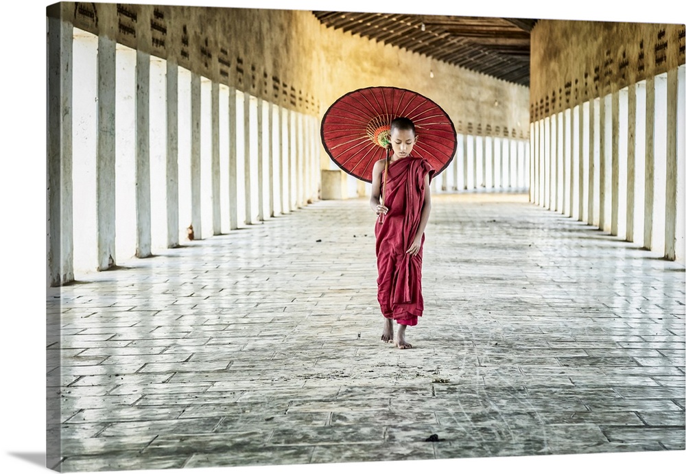 Burmese monk with parasol walking in his monastery