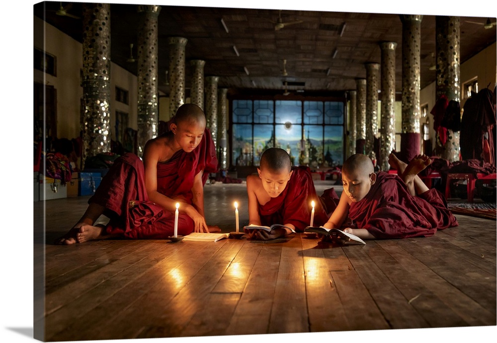 Burmese monks reading by candlelight in their monastery