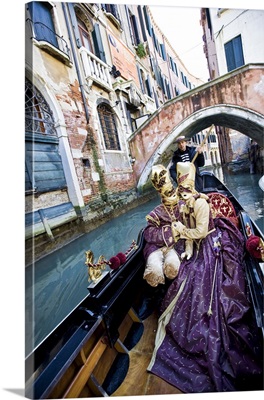 Couple in Masquerade outfits kissing in Gondola underneath bridge