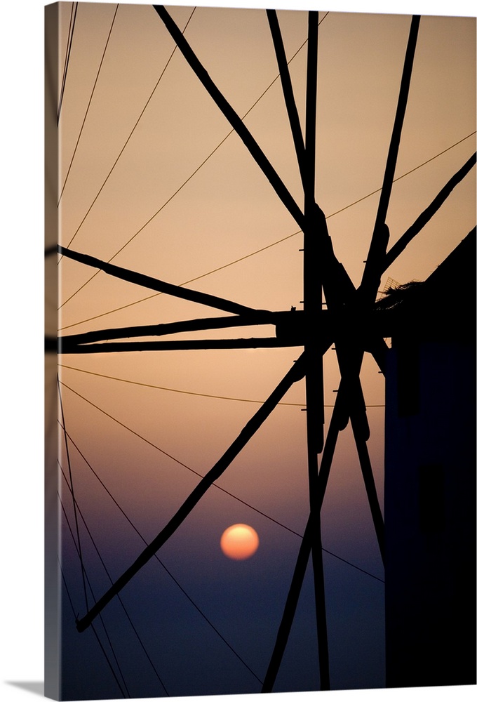 Giant, vertical, close up photograph of the spokes of a windmill at sunset, in Mykonos, Greece.