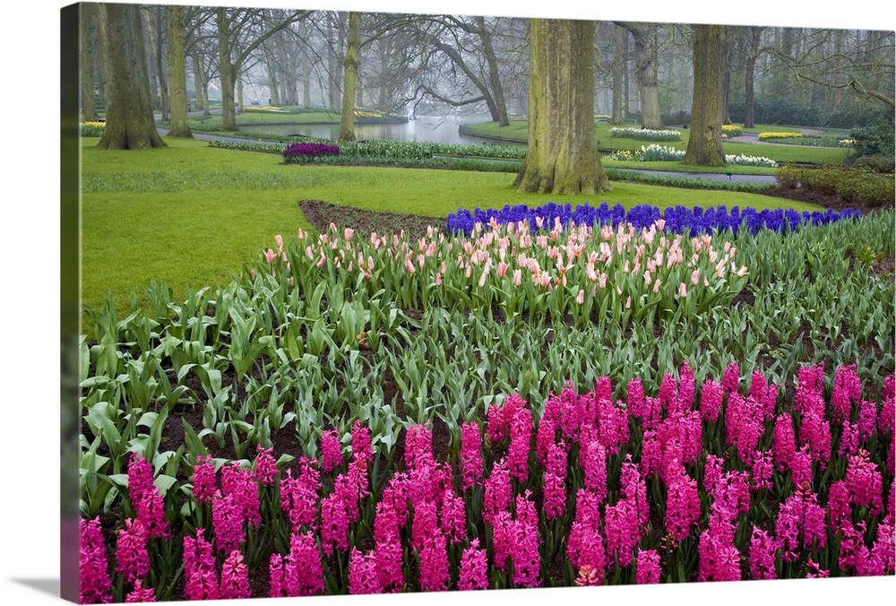 This is a landscape photograph of a garden full of carefully cultivated flowers in meticulously organized flower beds, a s...
