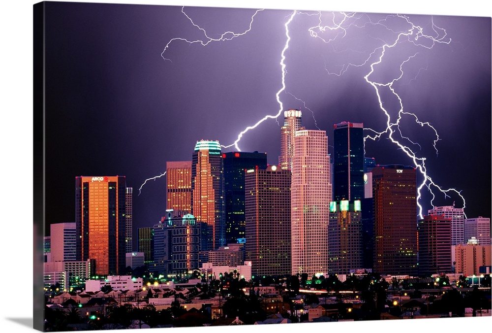 Photograph of lit up skyline at night with storm clouds overhead.