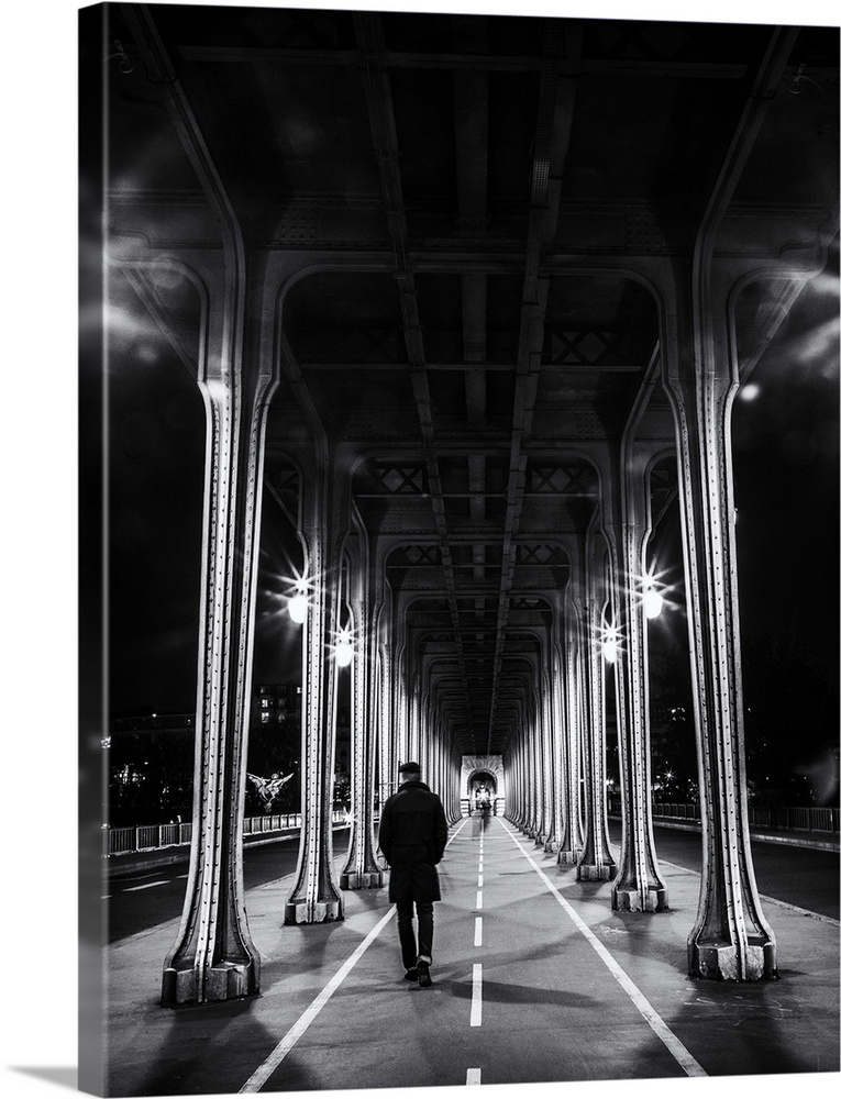 Black and white photograph of a man walking under an overpass in Paris.