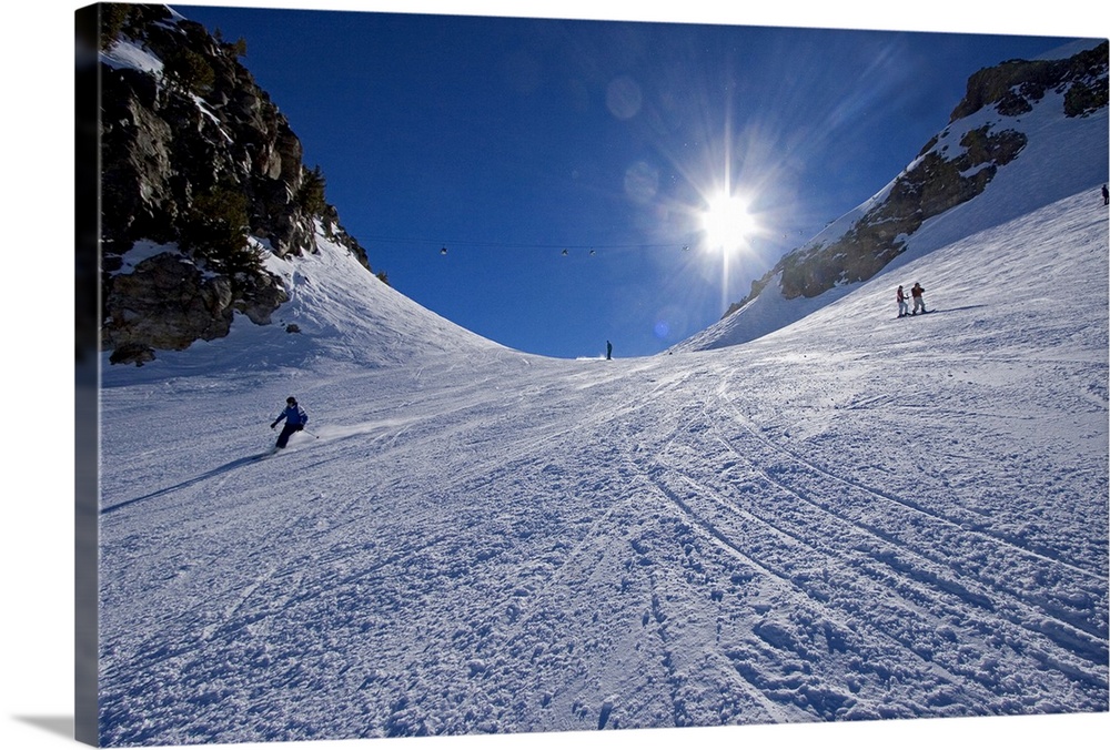 This large piece is a photograph taken from the bottom of a mountain and looking up toward the top where skiers are starti...