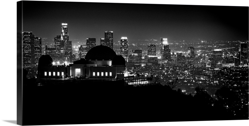 Large monochromatic photograph displays the busy skyline of a famous California city at nighttime.  The speckled lights co...
